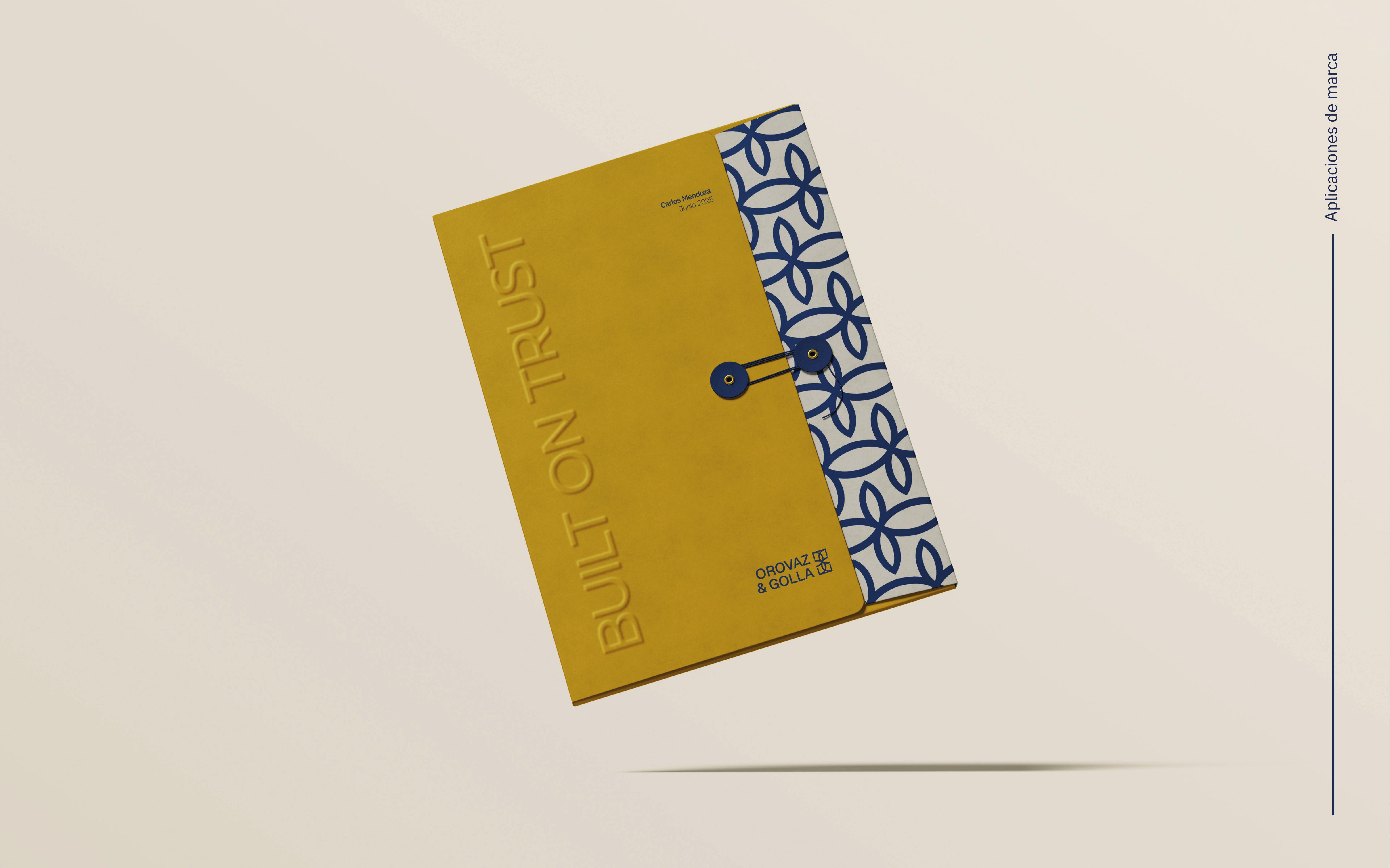 Carpeta amarilla con texto en relieve 'BUILT ON TRUST' y diseño azul de flores en fondo beige.
